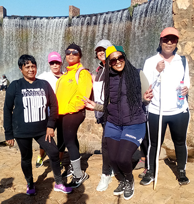 Avril with group of friends standing outside with hiking clothes and equipment.