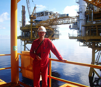 Brad wearing PPE standing in an offshore oil platform.