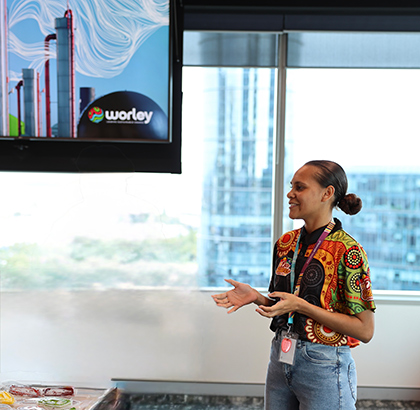 Cheroke standing next to a TV presenting.