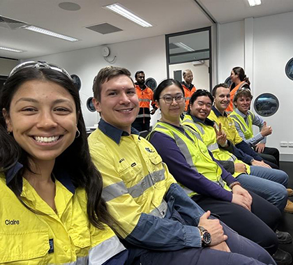 Claire sitting in a row of chairs with work colleagues all dressed in uniform.