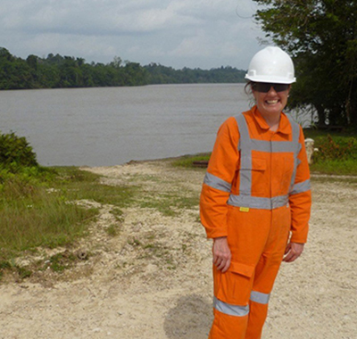 Clare wearing PPE standing in front of a body of water.