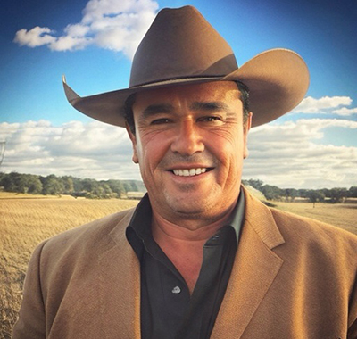Claudio wearing a brown cowboy hat standing on a field.