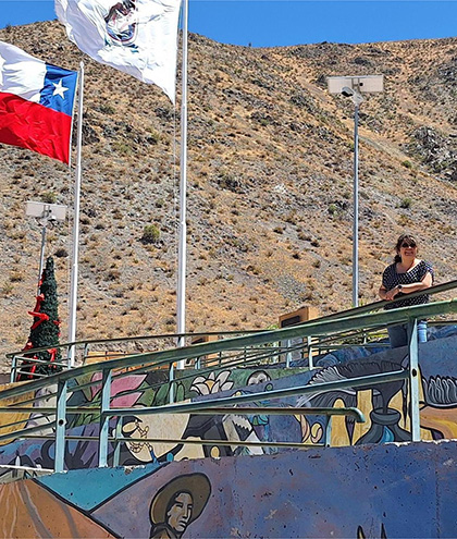 Consuelo standing on a ramp with colorful mural art, mountainous dry landscape in the background.