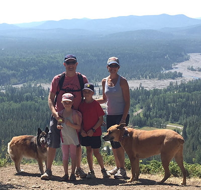 Gillian outside on a mountain with husband, two children and two dogs.