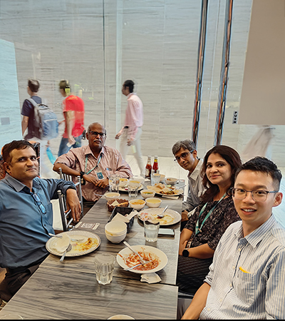 Guan with his colleagues sitting together at a restaurant table enjoying a team dinner