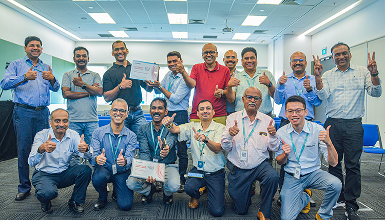 Guan and his colleagues smiling and giving thumbs up during a team recognition in office