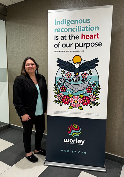 Linette standing next to a Worley Indigenous reconciliation banner.