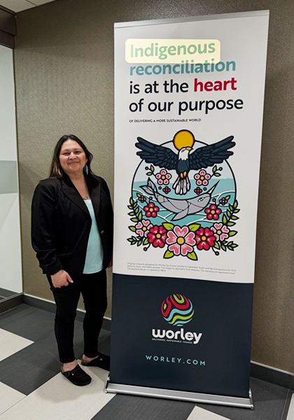 Linette standing next to a Worley Indigenous reconciliation banner.