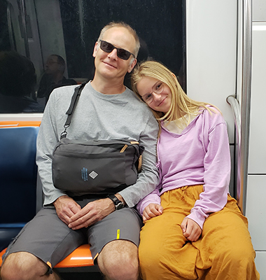 Michael sitting next to his daughter on a train.