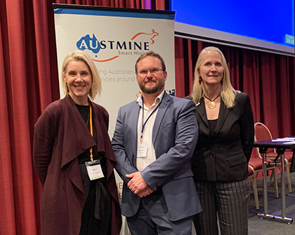 Nathan standing with two other people in front of an Austmine banner at a conference.