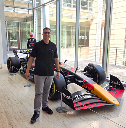 Serge standing next to a Formula One race car inside a building.