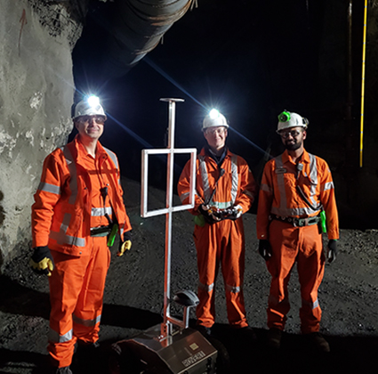 Serge and two colleagues wearing PPE and headlamps underground.