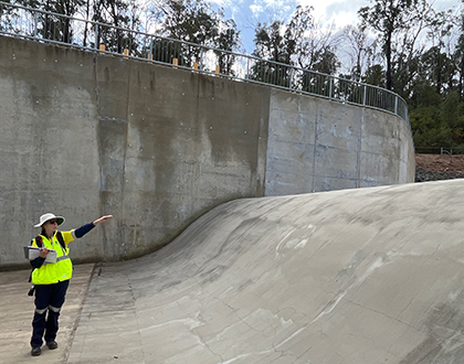 Sonel standing inside an empty dam wearing PPE, pointing.