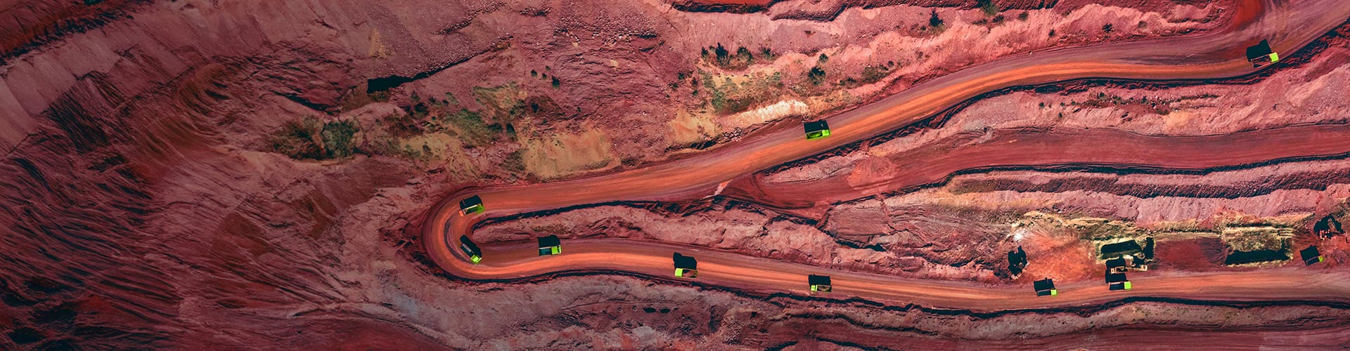 Aerial view of a mine with haul trucks driving along the road.