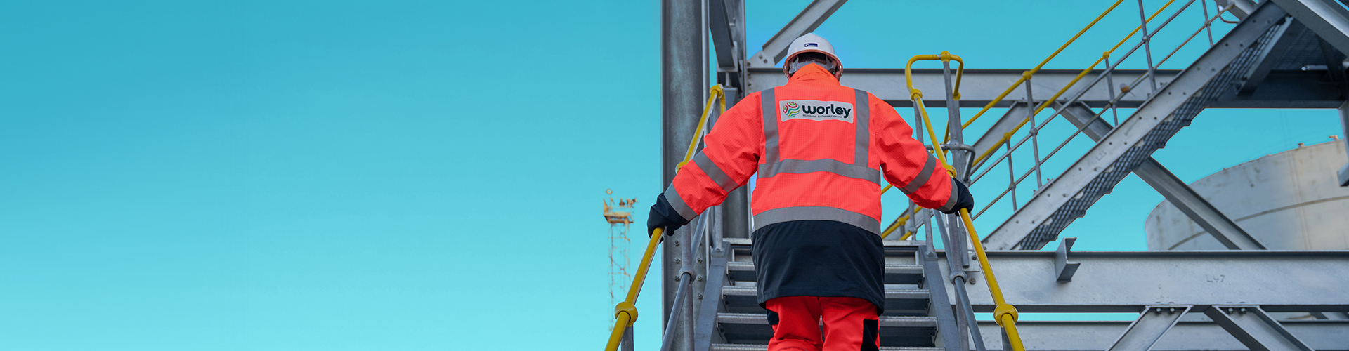 Person wearing PPE walking up stairs in a steel structure.