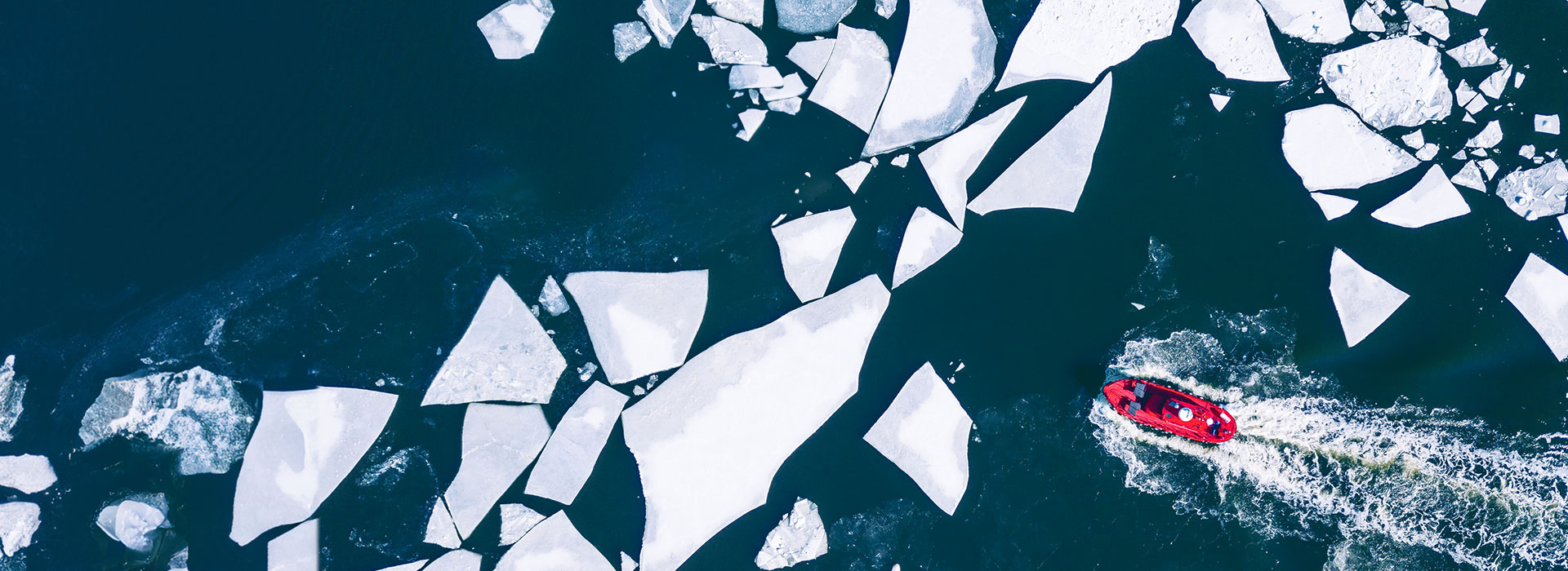 Bright boat cruising through water with shattered pieces of ice.