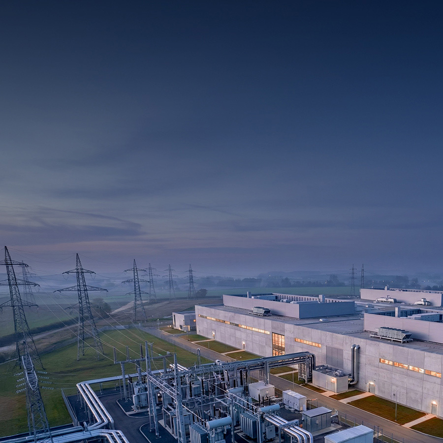 Aerial view of a large data center situated next to rows of power lines.