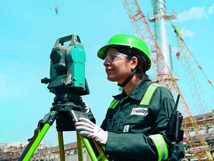 Worley woman wearing PPE standing behind a survey machine.