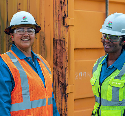 Two Worley women wearing PPE in front of a steel container.