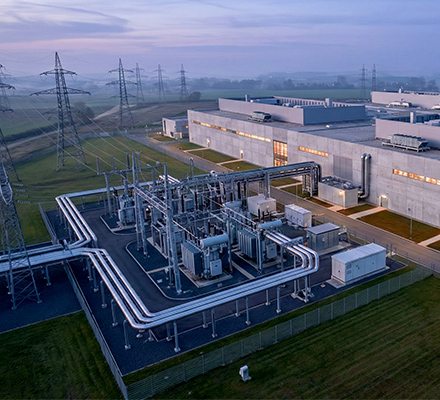 Aerial view of a large data center situated next to rows of power lines.