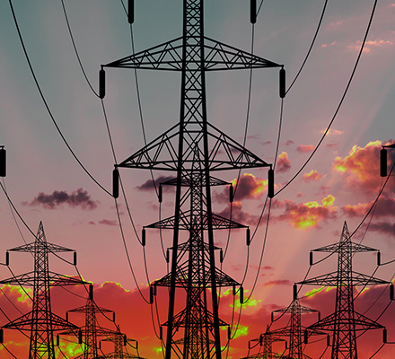 Rows of power line transmission towers with an orange sky.