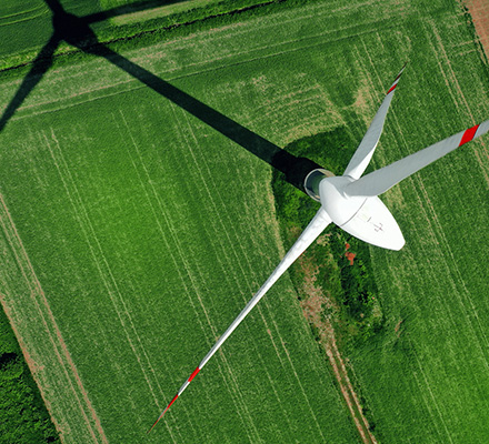Looking down on the top of a wind turbine in a green field.