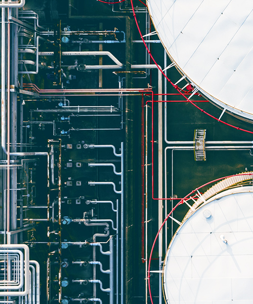 Aerial view of a refinery wth white tanks and green grass.