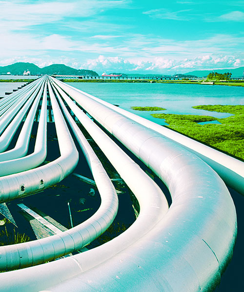 Petroleum pipes and oil tanker in the background at a pier.