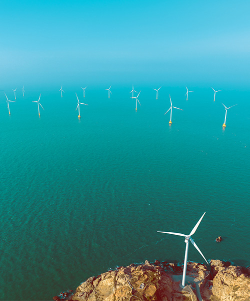 Wind turbine on the edge of a cliff overlooking the ocean.