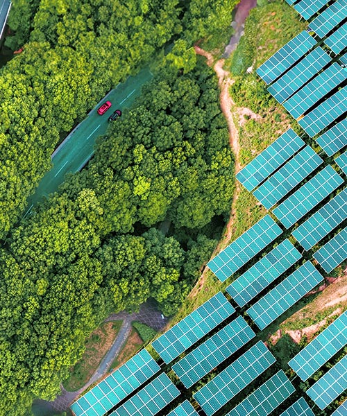 Aerial view of solar panels and two roads next to a forest.