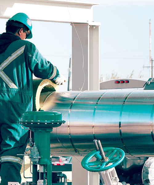 Worker wearing safety helmet working on a large steel pipe.