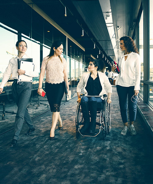 Four women travelling through an office, one in a wheelchair.
