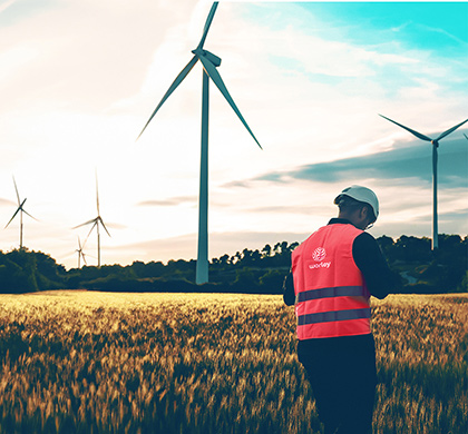 Person wearing Worley PPE next to a wind farm.