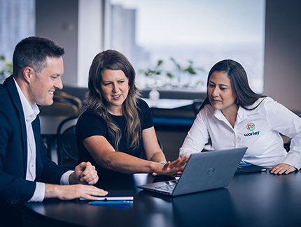 Three Worley people sitting together at a table looking at a laptop.