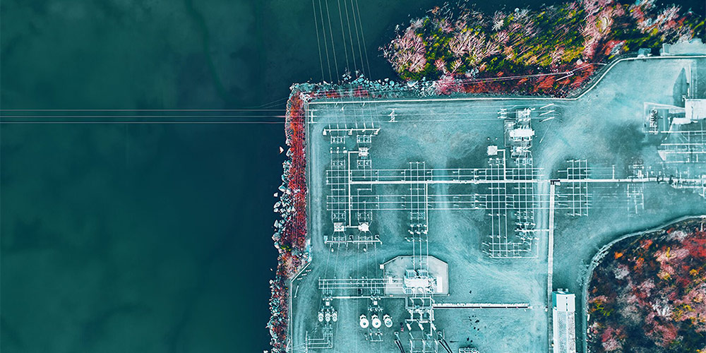 Aerial view of a power plant next to a body of water.