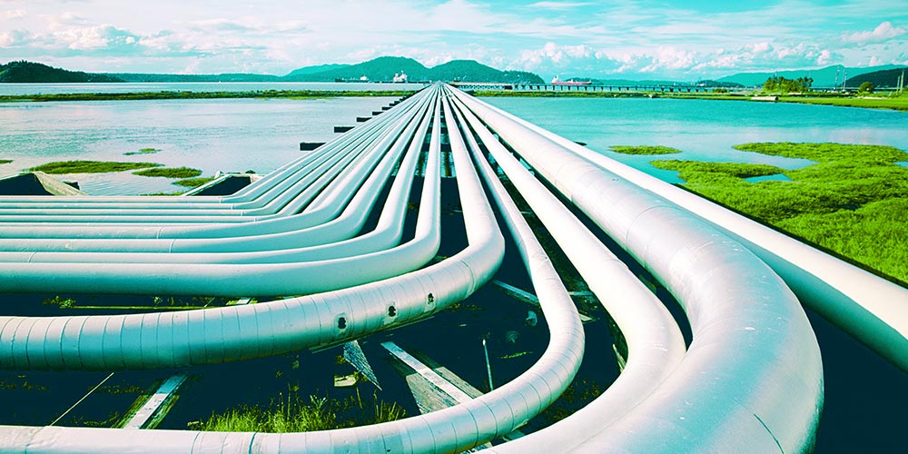 Petroleum pipes and oil tanker in the background at a pier.