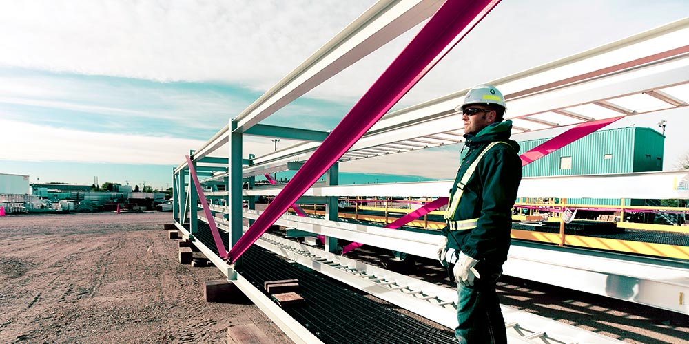 Construction worker wearing a hard hat standing next to a large metal structure.