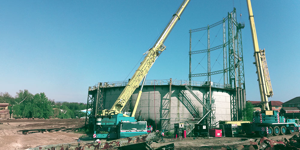 Gas holder being dismantled with cranes during the decommissioning process.