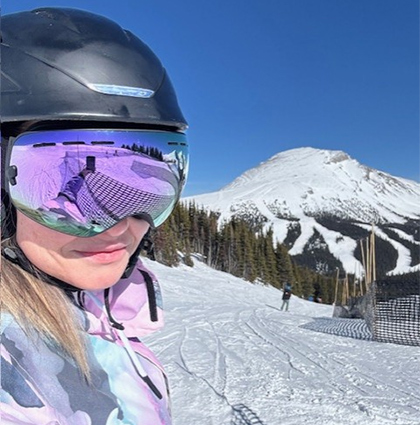 Cheryl wearing helmet and goggles on ski slopes.