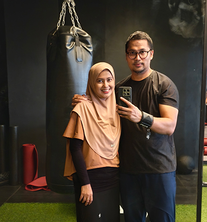 Febry standing with his wife inside a gymnasium.