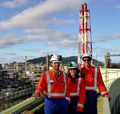 Harriet on site at an industrial facility next to two colleagues, wearing safety gear during an earlier role.