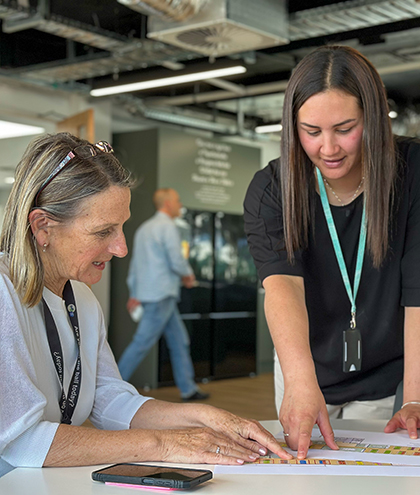 Kaitlin and a colleague at a desk looking at an office seating plan.