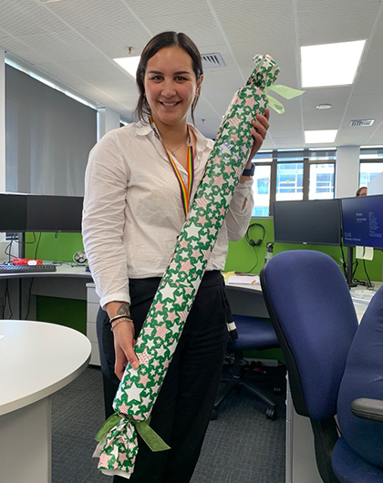Kaitlin inside the office holding a Christmas-wrapped present.