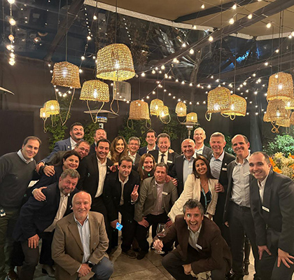 Manuel standing with a large group of colleagues underneath handing light shades with twinkling lights.