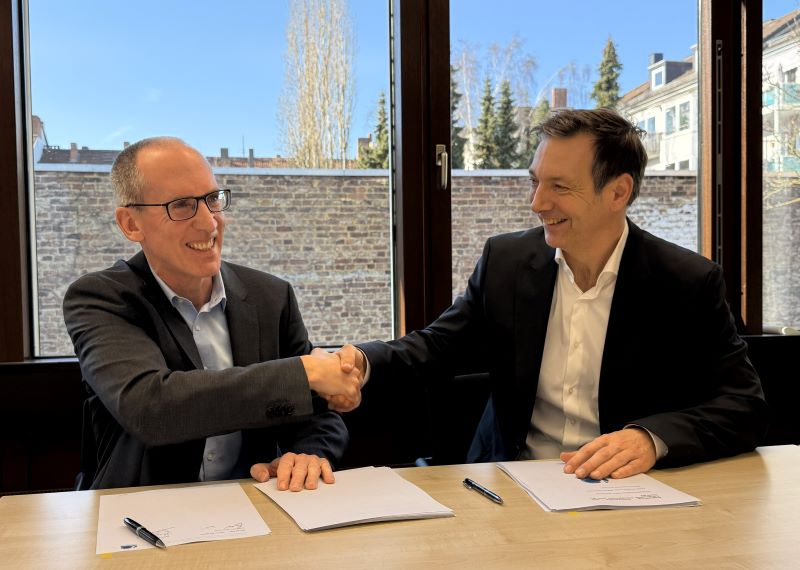 Two people from Aquaductus and Worley sitting together at a table shaking hands.