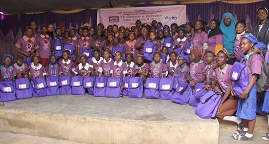 Large group of young female students in the FunSTEM program in Nigeria, holding purple backpacks, with their female teachers.