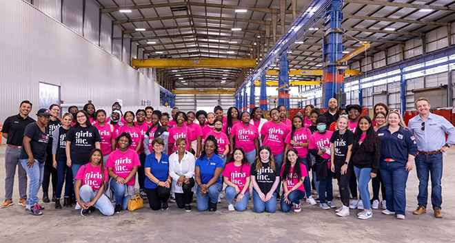 Group of female high school students, teachers from Girls Inc and Worley employees inside the modularization and fabrication hub.