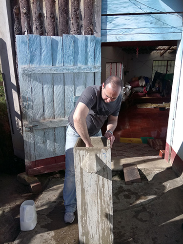 Volunteer working with his hands in a concrete tub.