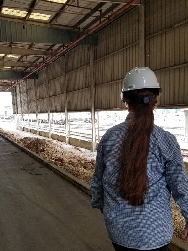 Person wearing a hard hat and HoloLens augmented reality headset looking down the length of a building.