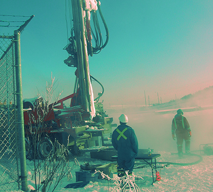 Two workers with machinery in the snow.